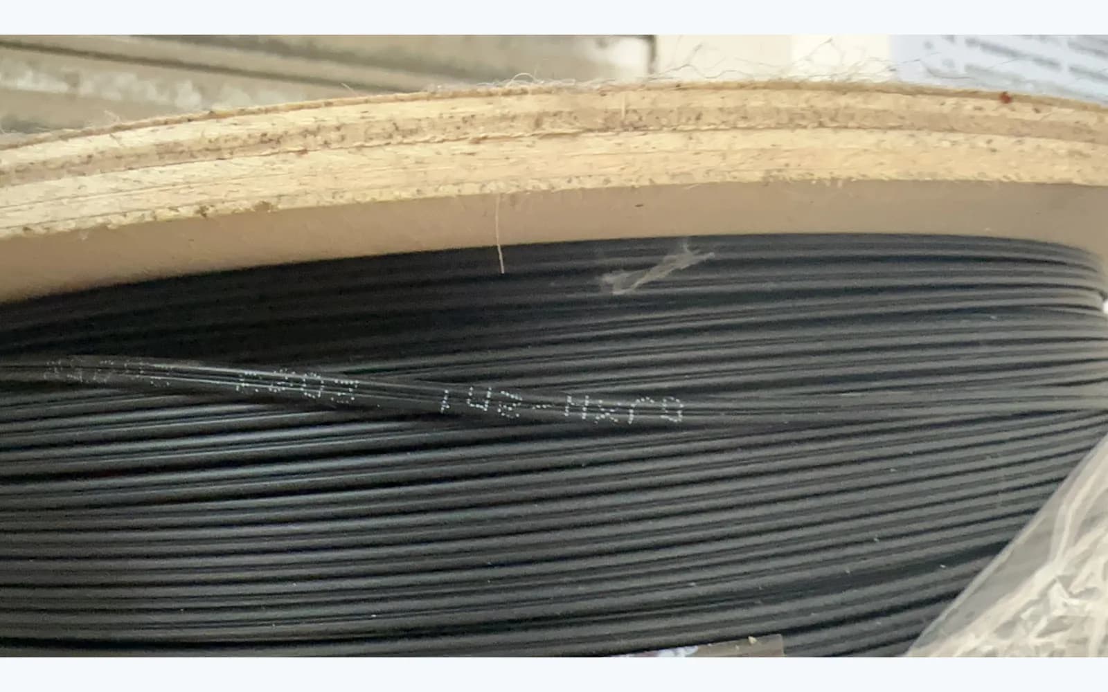 Black cable wound on a wooden drum, a factory product example whose appearance does not establish PE or track-resistant sheath performance